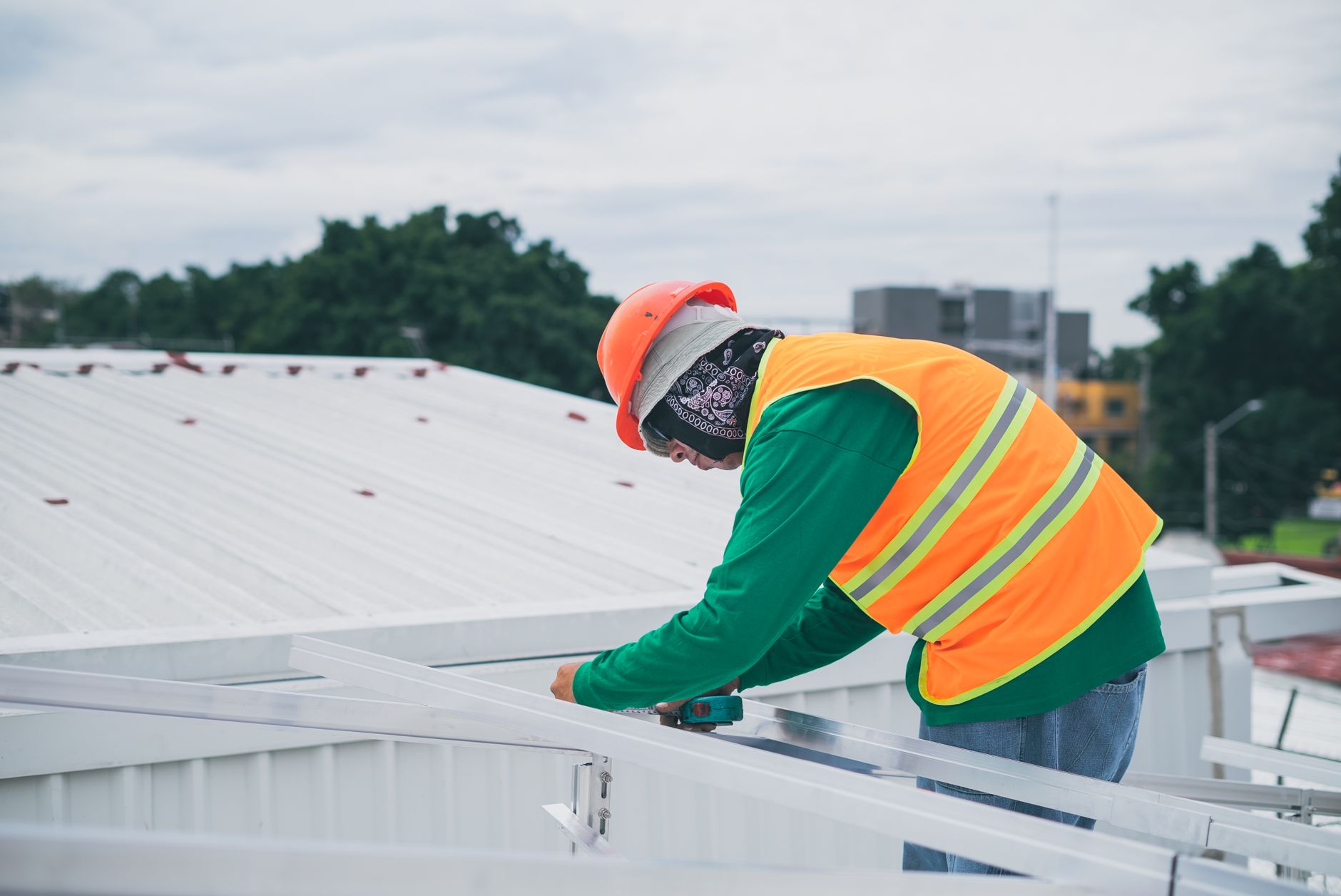 A Royal Peak Roofing crew member safely working on a steep-pitched roof of a Woburn colonial home, performing asphalt shingle replacement.